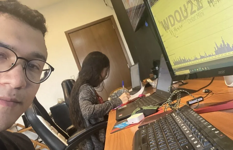 Daniel e Sarah no escritório, com o gráfico do mini dólar na tela